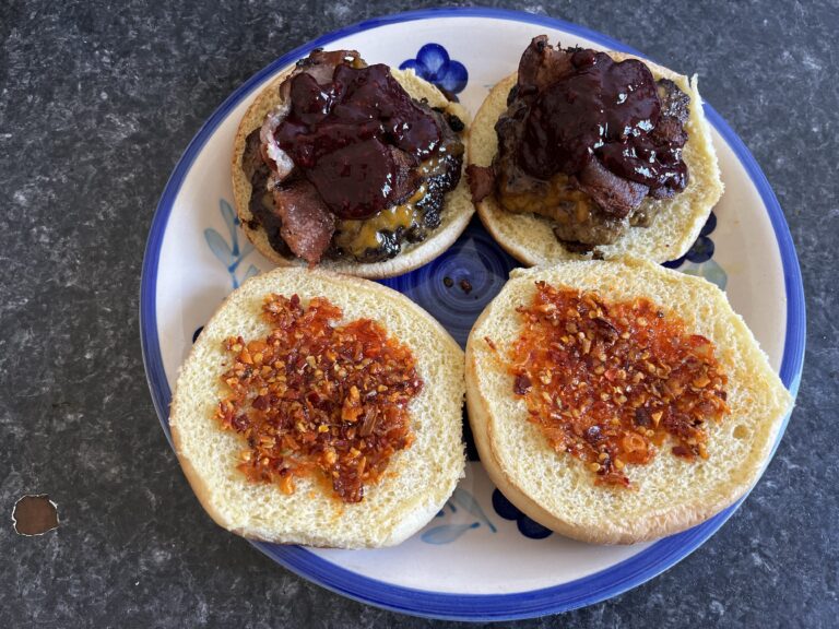 Cheeseburger with Cheddar, Bacon, and homemade Blackberry Sauce. Bun has Spicy Chili Crunch spread on it.